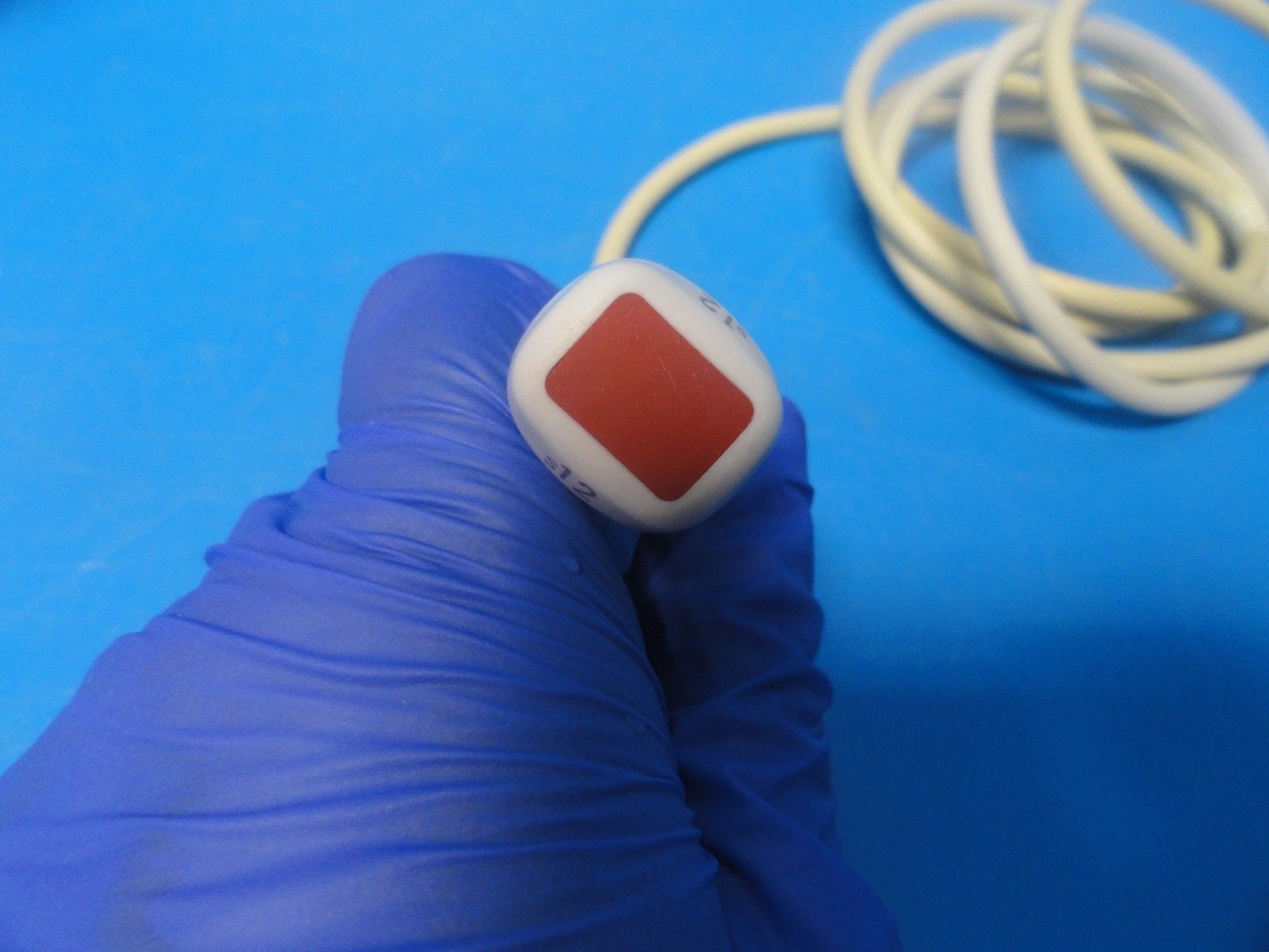 a gloved hand holding a red and white button
